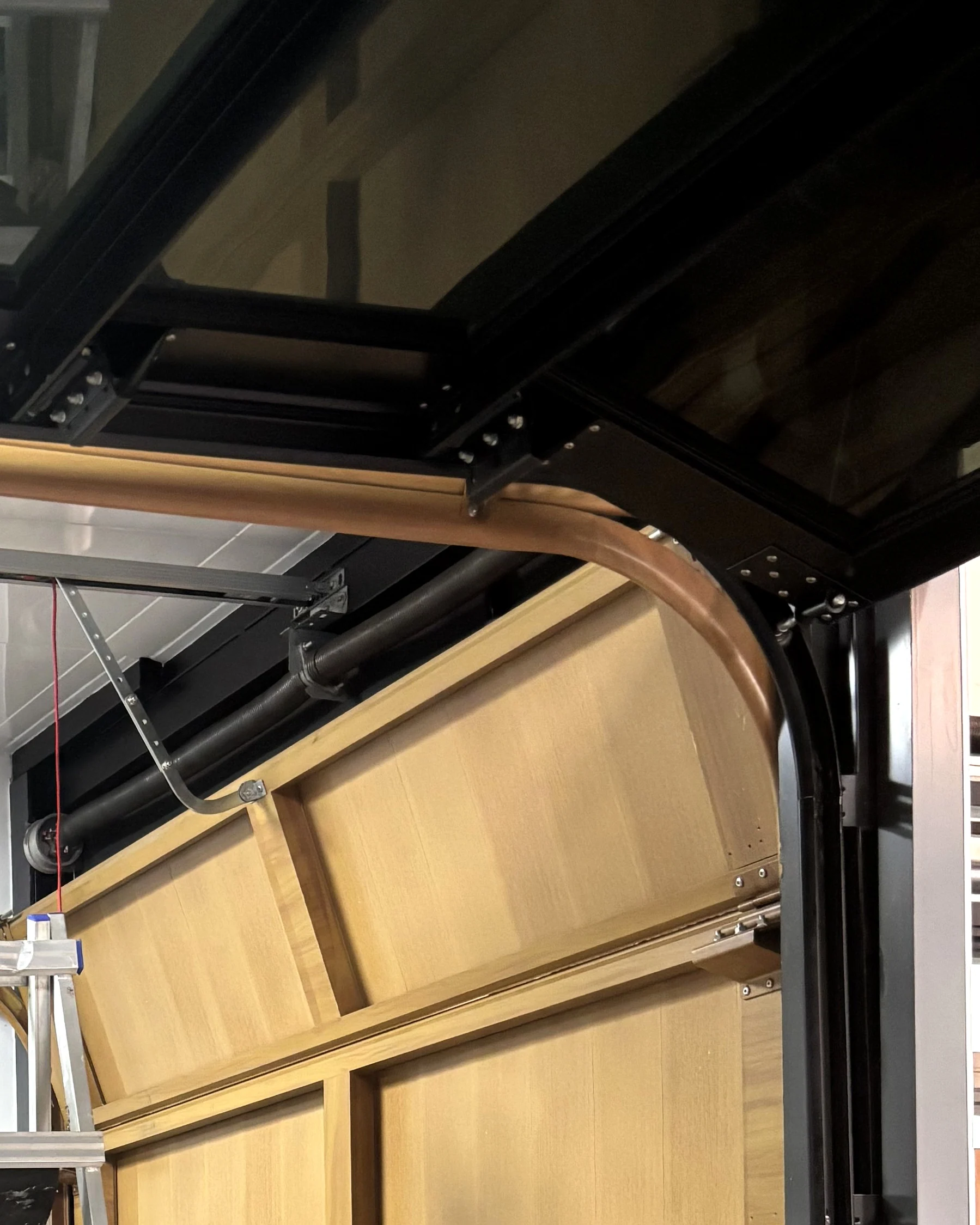 Photographed overhead garage-door track and panel connection; model not identified